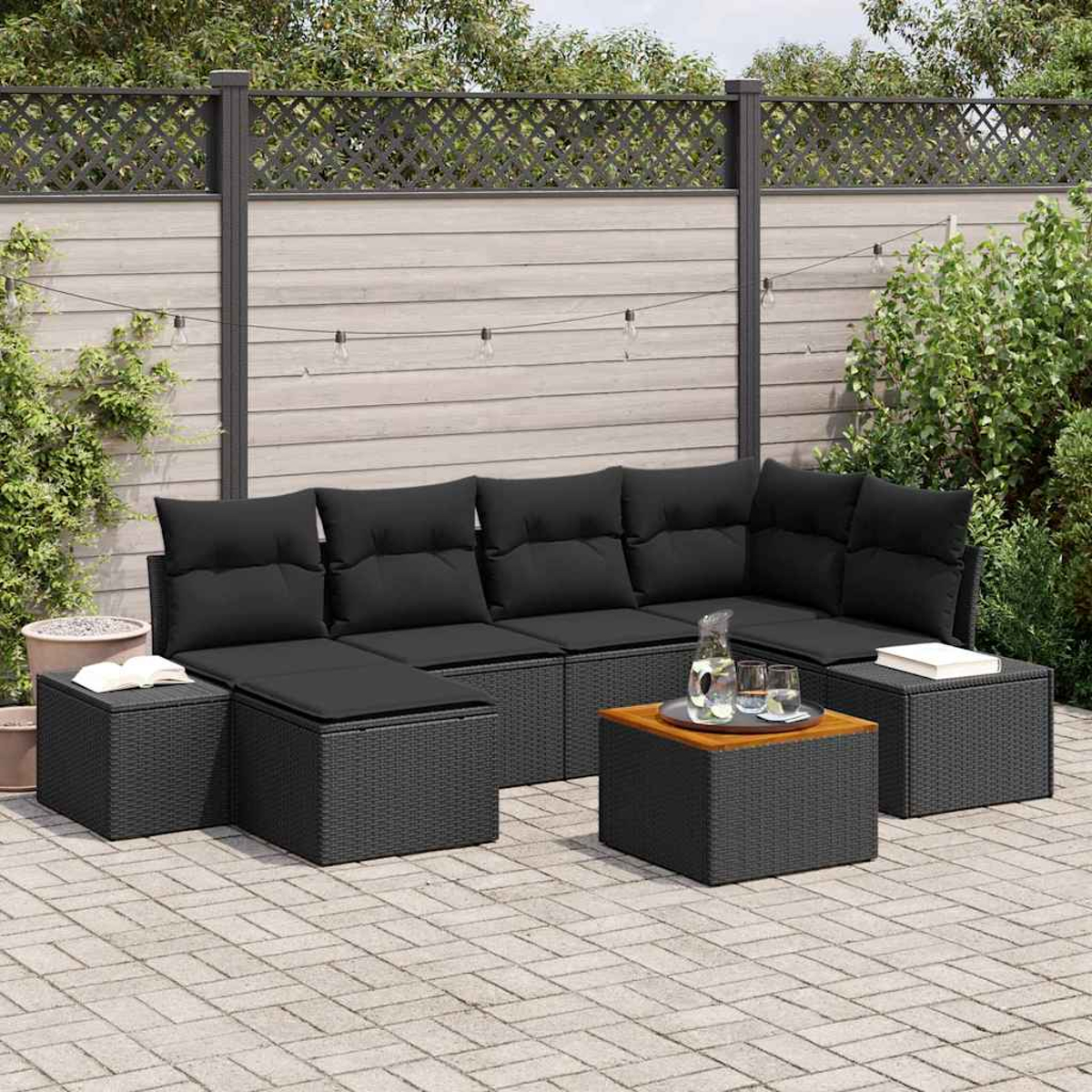 Outdoor-Garnitur aus schwarzem Korbgeflecht auf einer Terrasse. Enthält Ecksofa, Ottomanen und Couchtisch. Hintergrund mit Zaun und Grün.