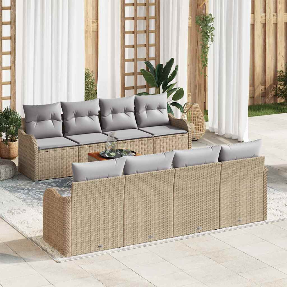 Outdoor-Sitzgruppe mit gewebten beigefarbenen Rahmen und grauen Kissen. Beinhaltet zwei Sofas und einen kleinen Tisch, auf einer Terrasse mit weißen Vorhängen.