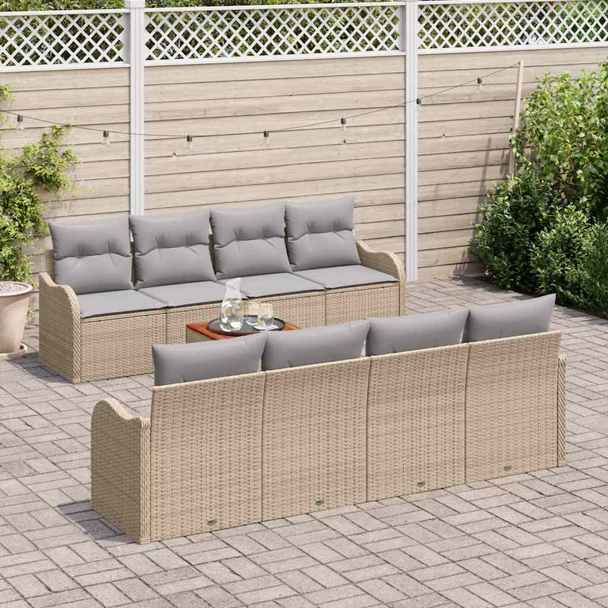 Szene auf der Terrasse im Freien. Zwei Korbsitzgruppen mit grauen Kissen, ein kleiner Tisch mit Getränken und ein Holzzaun im Hintergrund.