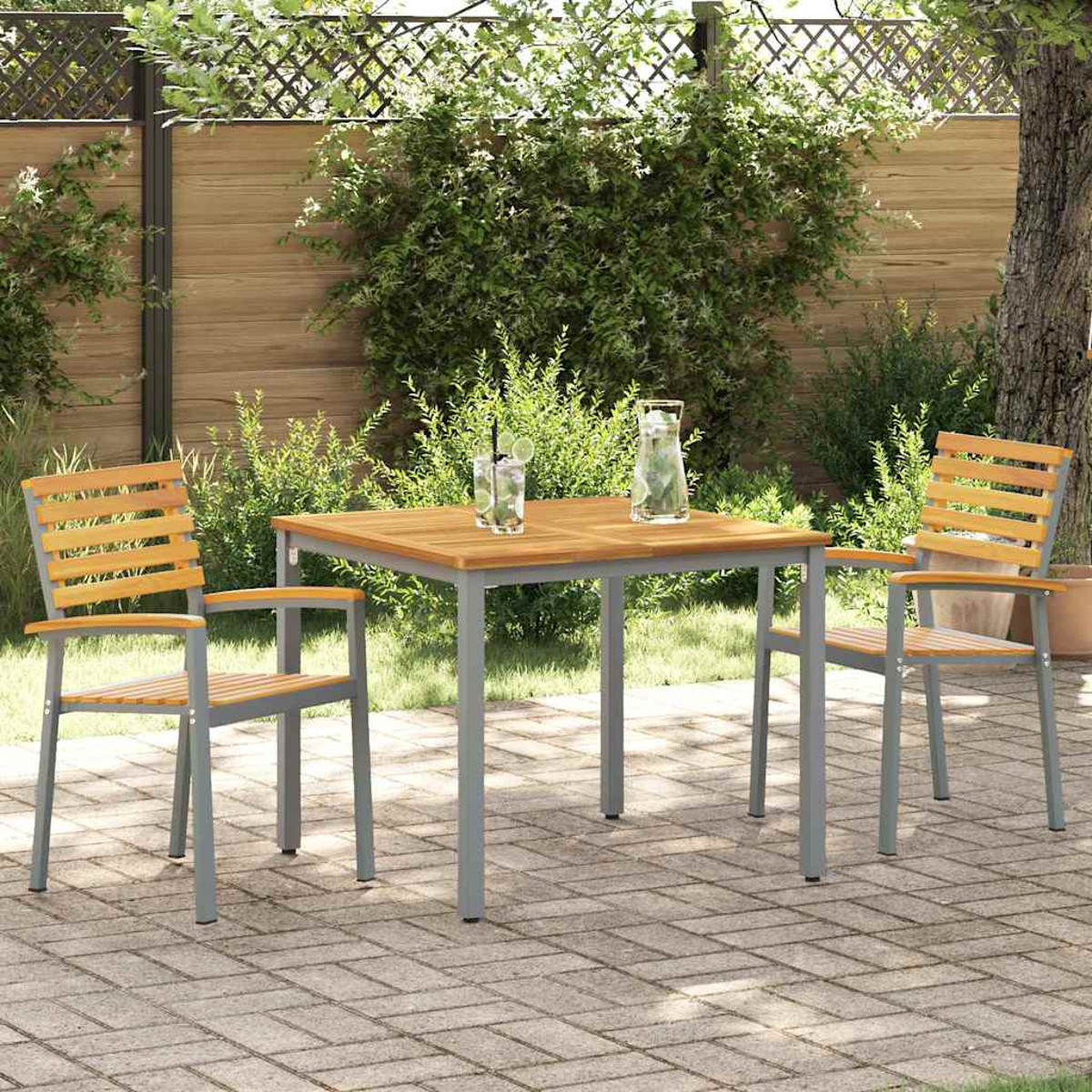 Garten-Terrassenset mit Tisch und zwei Stühlen. Getränke stehen auf dem Tisch. Im Hintergrund grünes Laub und ein Holzzaun.