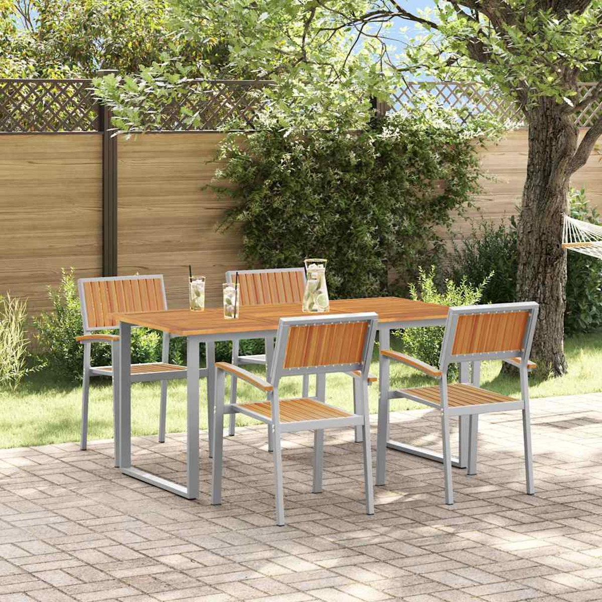 Essgruppe im Freien mit Holztisch und Stühlen. Getränke auf dem Tisch. Ziegelterrasse, Bäume und ein Zaun im Hintergrund.