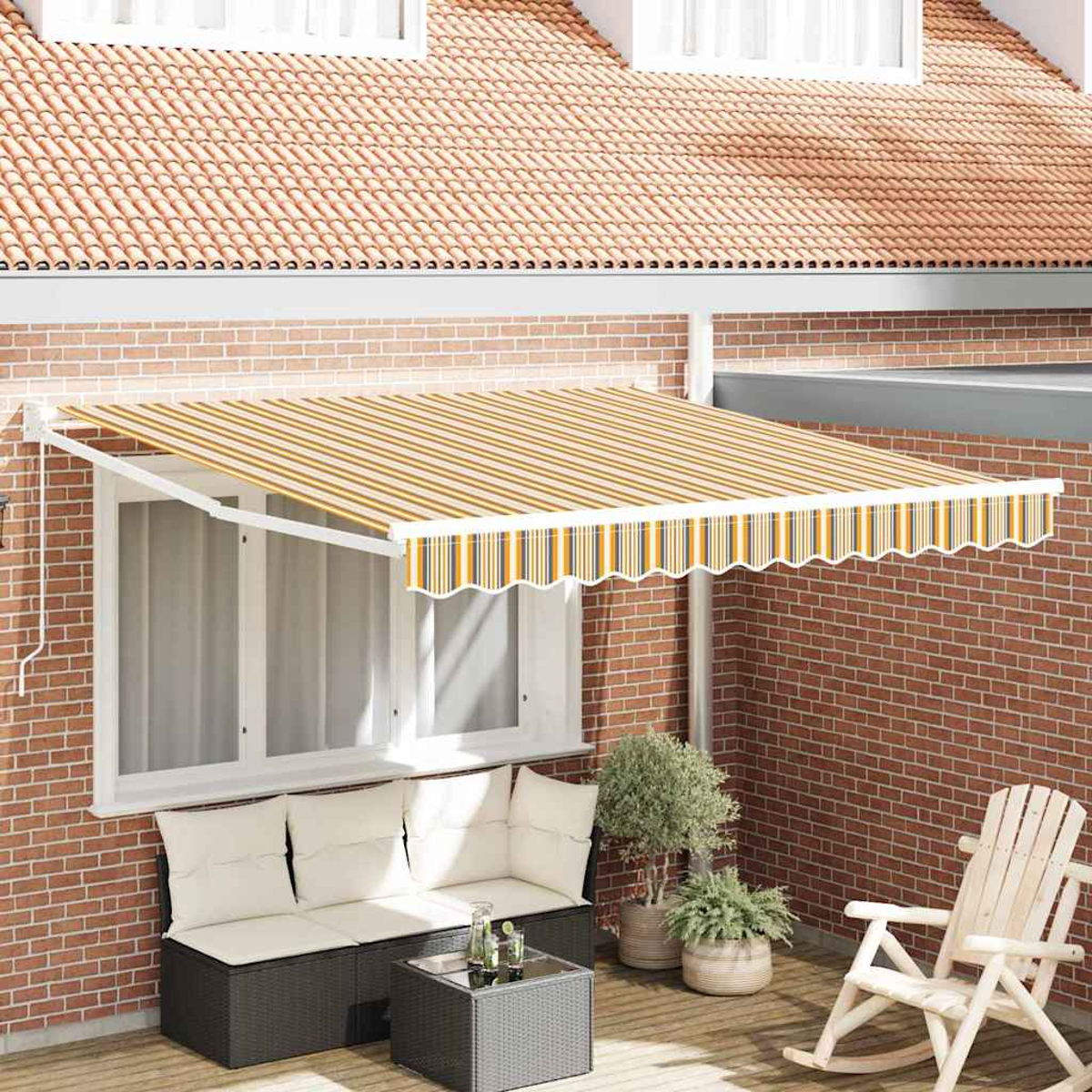 Una tenda a strisce si estende su un patio con mobili, piante e una sedia a dondolo. Un muro di mattoni e un tetto di tegole formano lo sfondo.