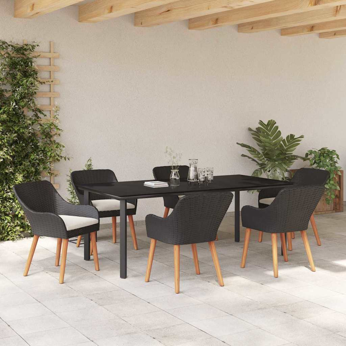Essgruppe im Freien: schwarzer Tisch und Stühle. Pflanzen rahmen die Terrasse ein. Helle Holzbalken und weiße Wände.
