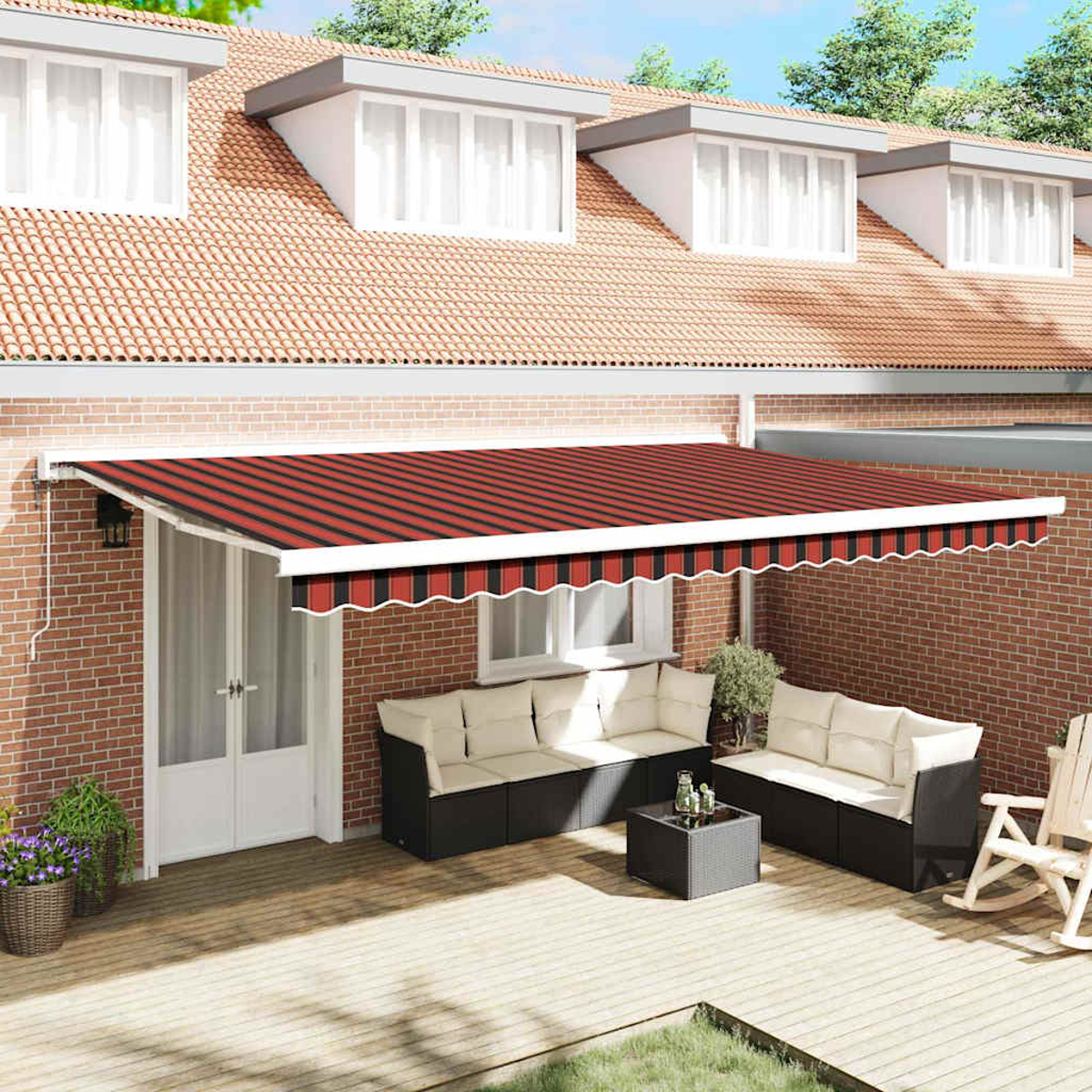 Eine Terrasse mit rot gestreifter Markise, Möbeln und einer Backsteinmauer. Im Hintergrund ein Haus mit Dachgauben.