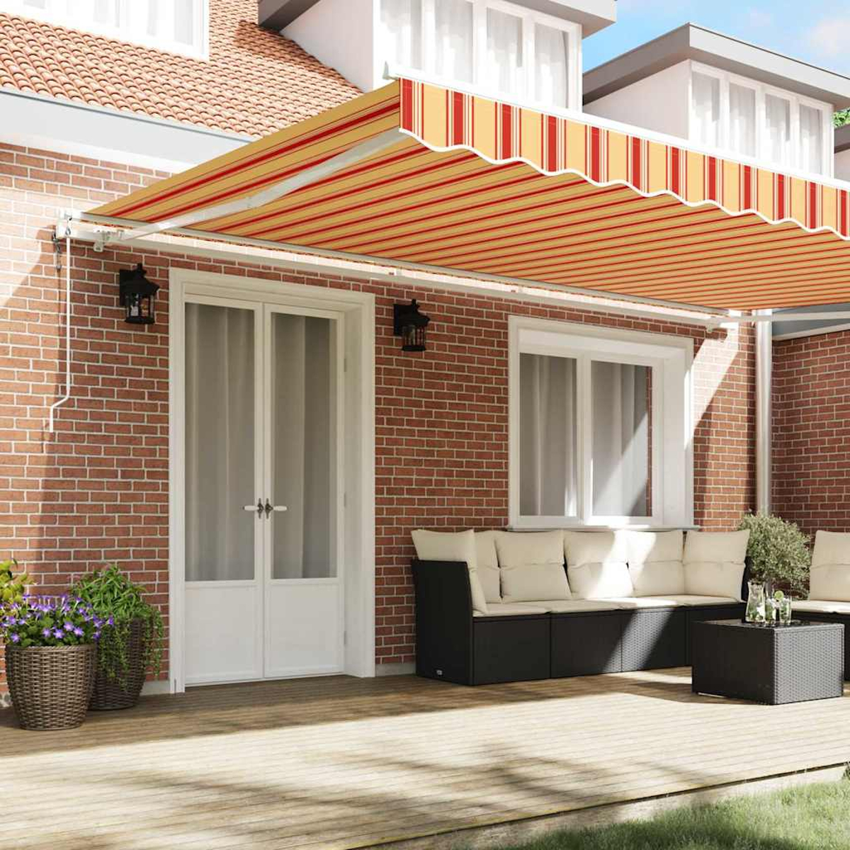 Eine Terrasse mit einem rot-gelb gestreiften Markise. Es gibt eine weiße Tür, eine Backsteinmauer, ein schwarzes Sofa und Topfpflanzen.