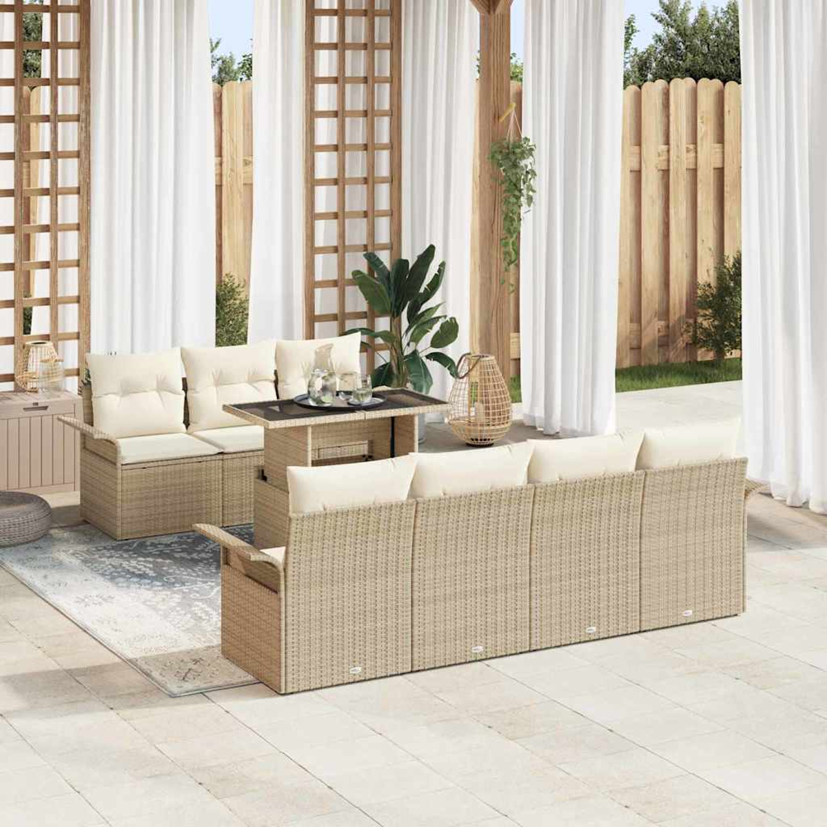 Terrassenset mit beigen Korbmöbeln, cremefarbenen Kissen und einem Tisch mit Glasplatte. Weiße Vorhänge und Holzzaun im Hintergrund.