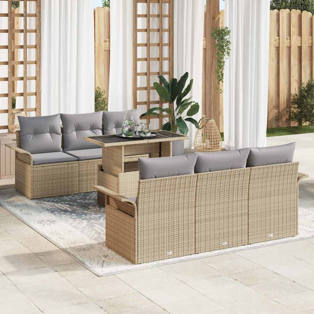 Szene im Freien mit Korbmöbeln: Sofas, Tisch und Teppich. Graue Kissen, weiße Vorhänge und Holzstrukturen sind vorhanden.