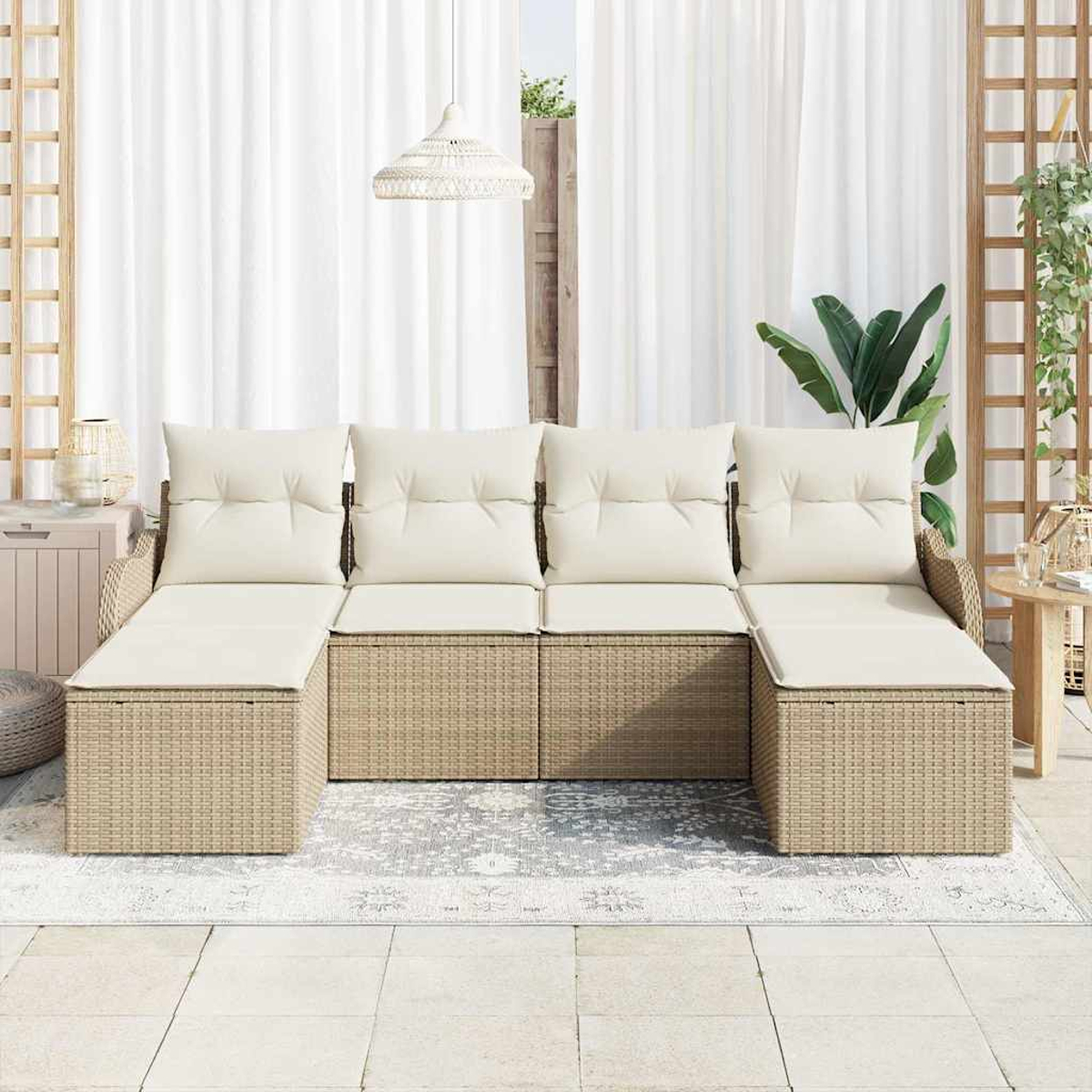 Sofá seccional de mimbre para exteriores con cojines crema. Incluye alfombra, cortinas y lámpara colgante. Se ven plantas verdes y un enrejado de madera.