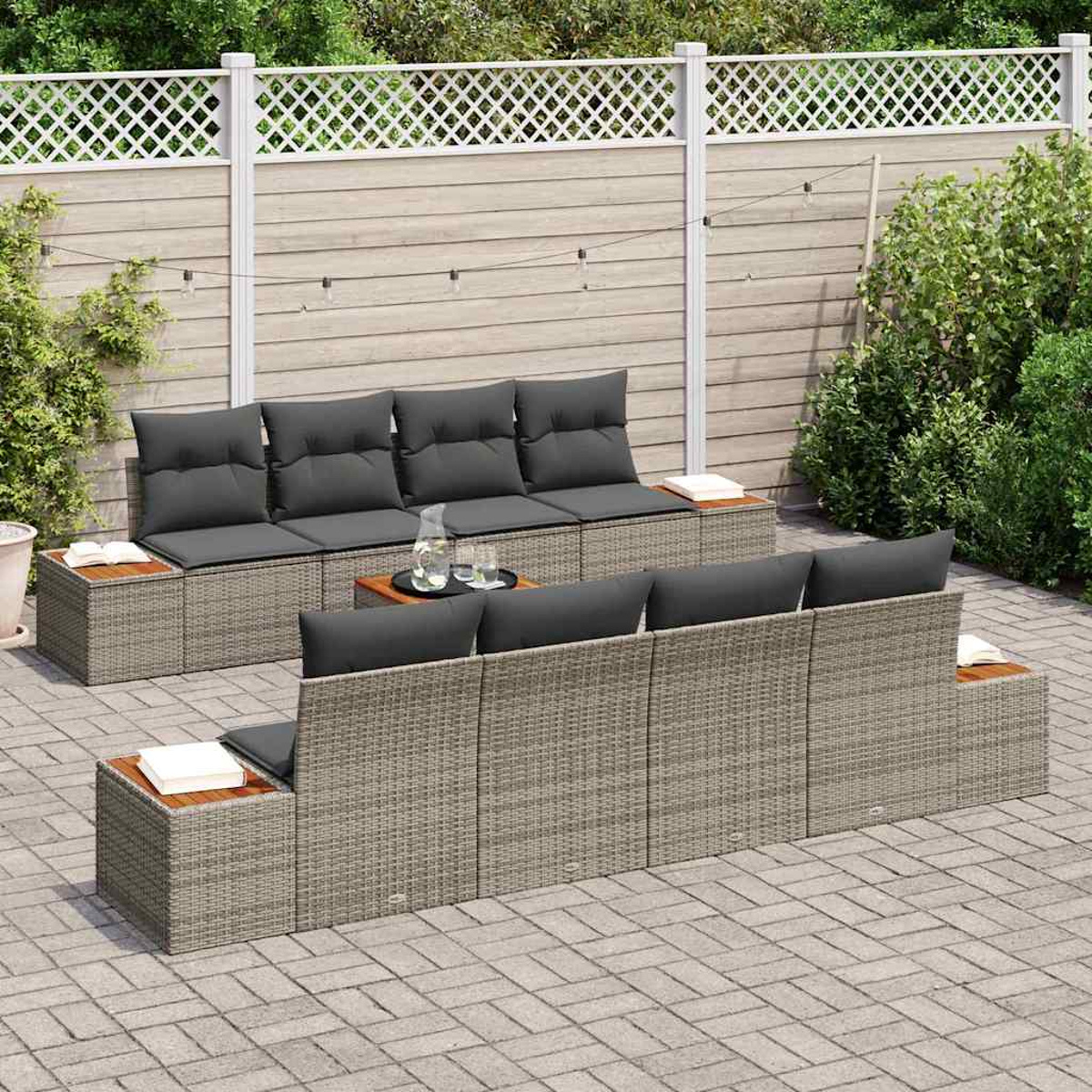 Outdoor-Sitzgruppe mit grauen Kissen und gewebter Basis. Enthält einen Tisch mit Getränken und einen Hintergrund aus einem Gitterzaun.