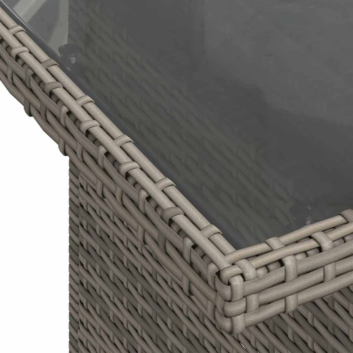 Nahaufnahme eines grauen Rattantisches mit Glasplatte. Die Ecke des Tisches ist sichtbar und zeigt gewebte Textur und eine klare, reflektierende Oberfläche.
