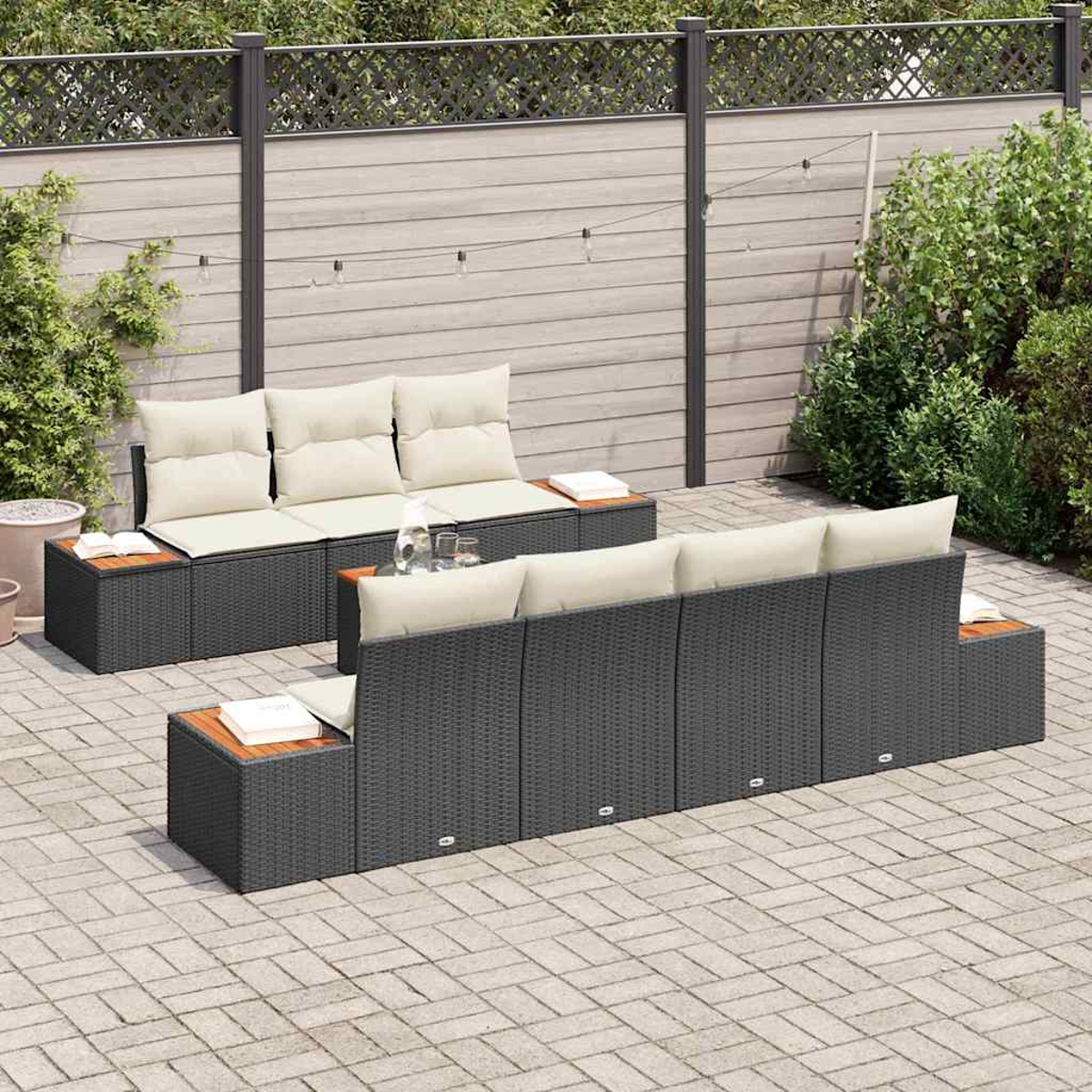 Gartenmöbel-Set: dunkelgraue Sofas mit cremefarbenen Kissen, Holztischen. Ziegel-Terrasse mit Holzzaun im Hintergrund.