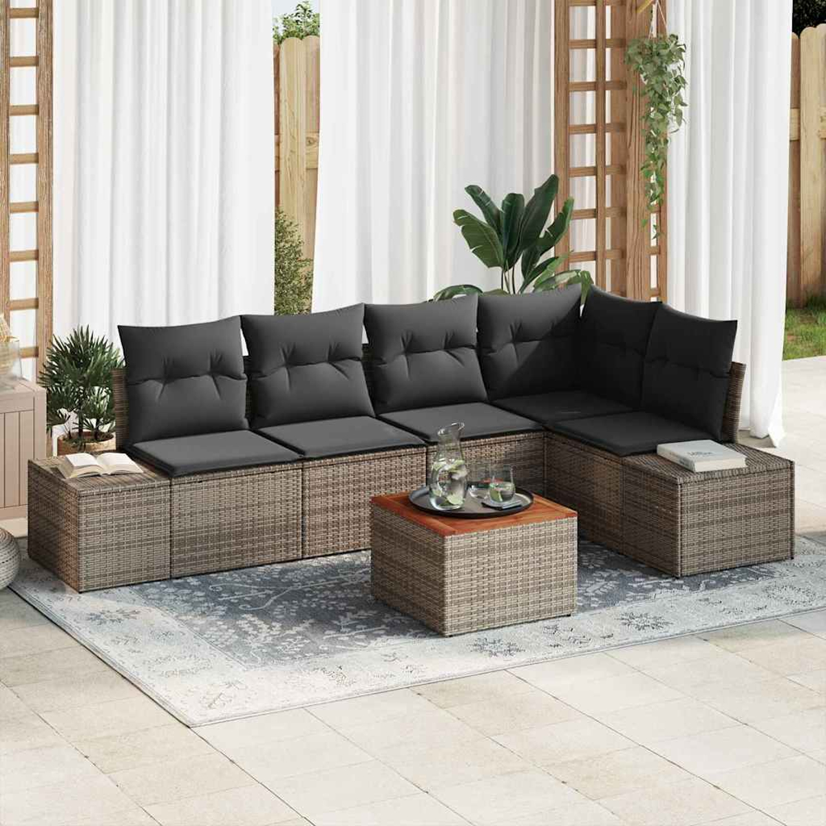 Outdoor-Sitzbereich: graues Ecksofa mit schwarzen Kissen, Korbtisch, Teppich, weiße Vorhänge und Pflanzen.