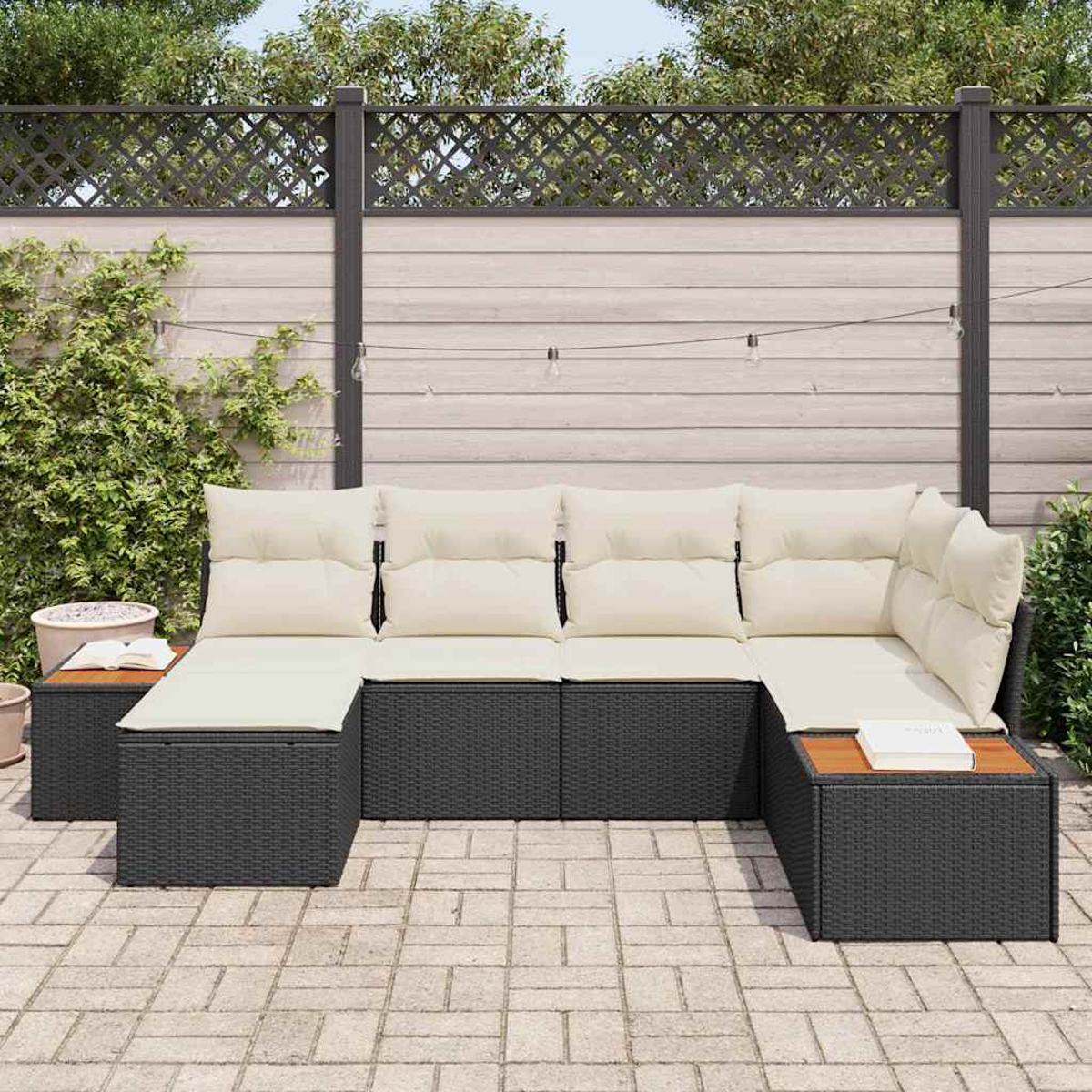 Sofá seccional al aire libre con cojines crema en un patio. Una mesa auxiliar de madera tiene un libro. Fondo muestra valla y plantas.