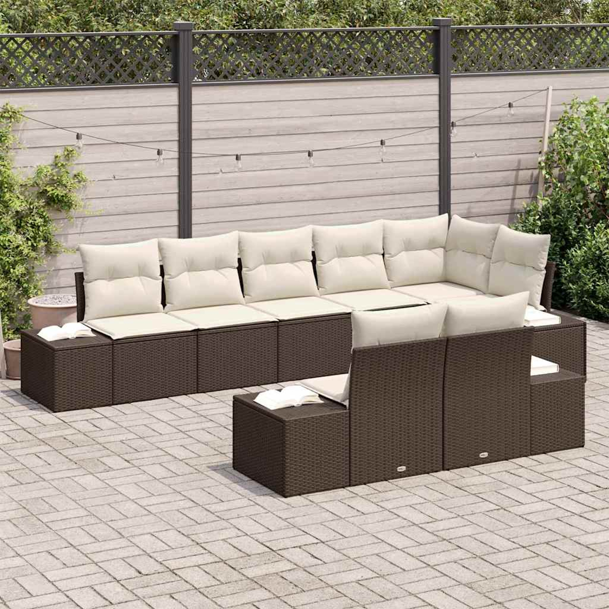 Outdoor-Sofa-Set aus braunem Korbgeflecht mit cremefarbenen Kissen auf einer Steinterrasse. Hintergrund sind Zaun und Grün.