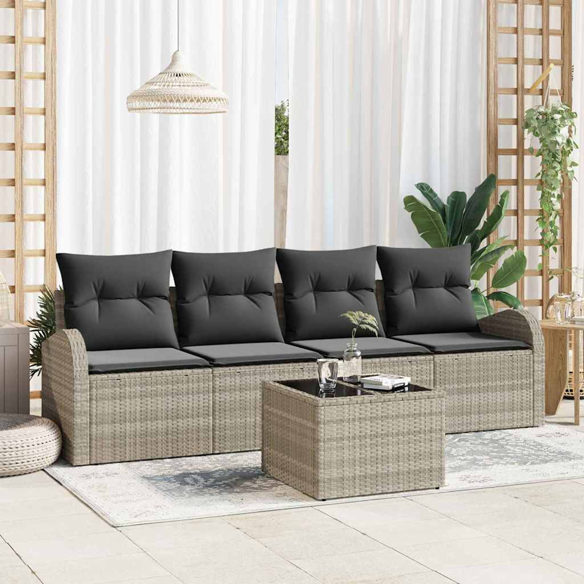 Outdoor-Sitzgruppe mit grauen Kissen und einem Couchtisch. Vorhänge und Pflanzen im Hintergrund.