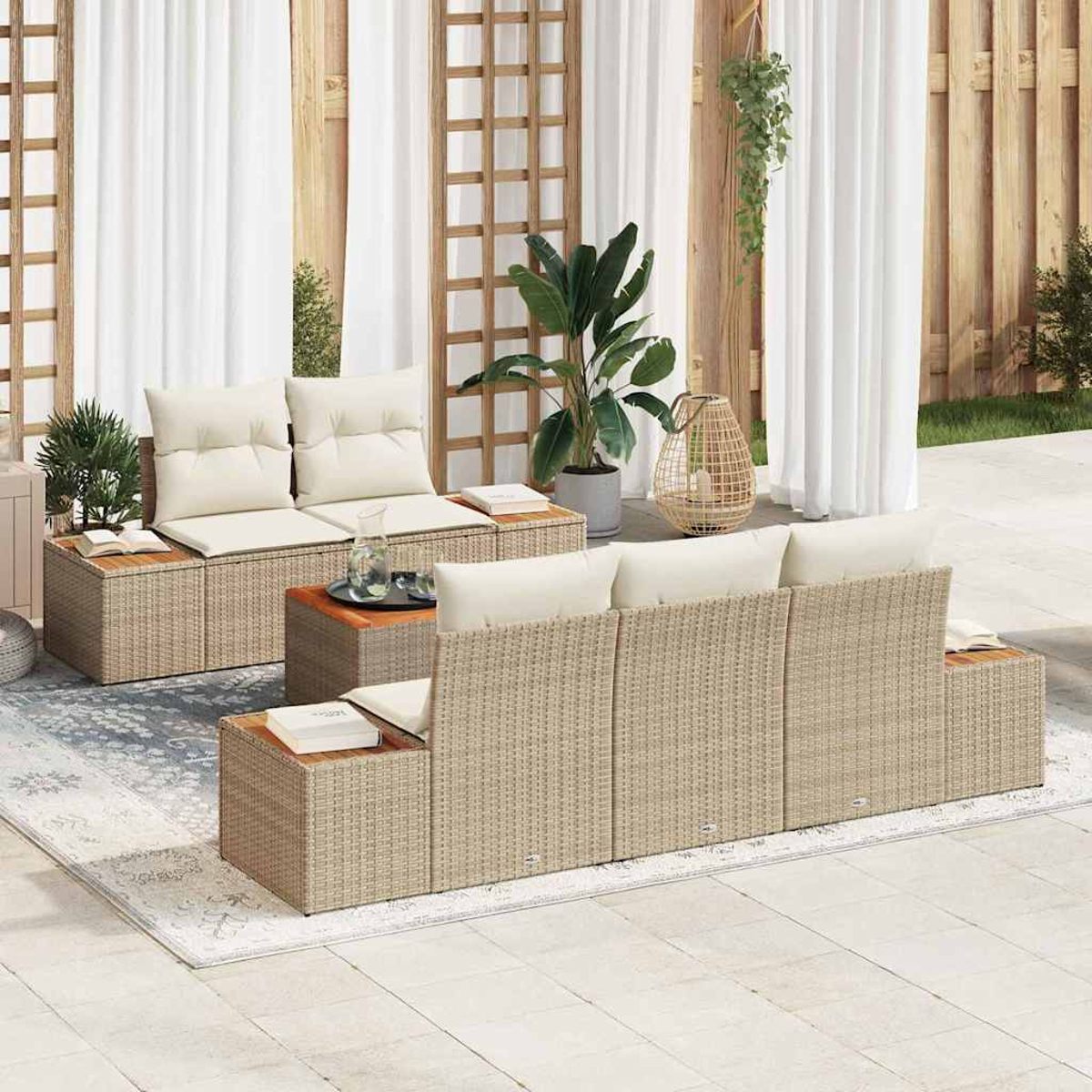 Zona de estar al aire libre con muebles de ratán y cojines blancos. Incluye sofá, dos sillas y mesa de centro, plantas y alfombra.