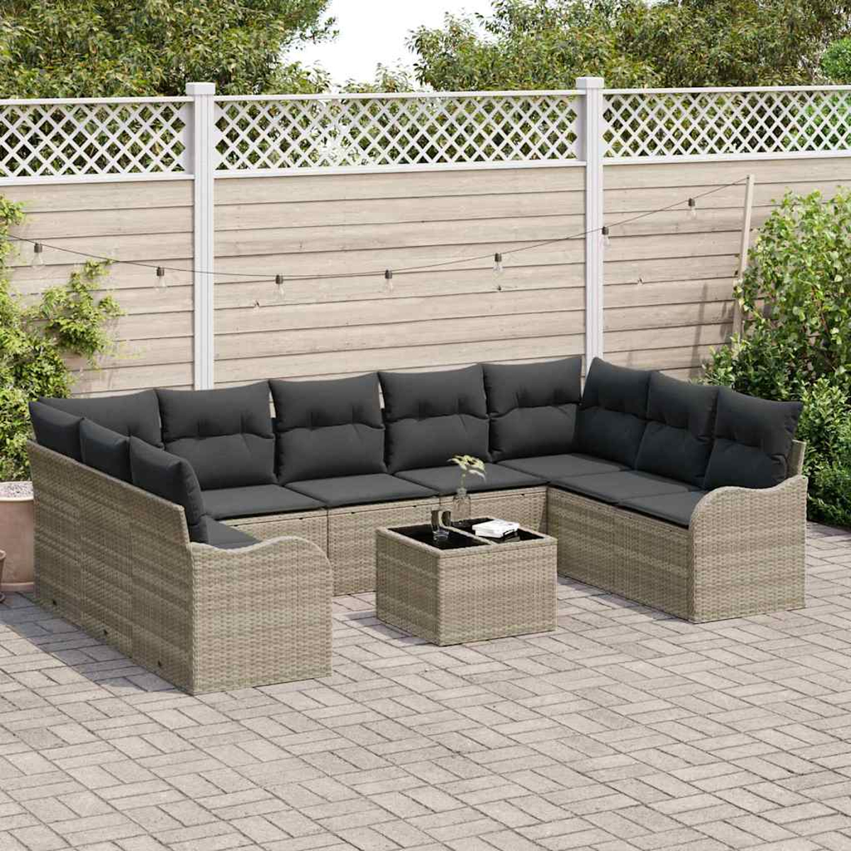 Ein Sitzbereich im Freien mit einem Ecksofa, einem Couchtisch und einem Zaun im Hintergrund. Das Sofa hat graue Kissen.