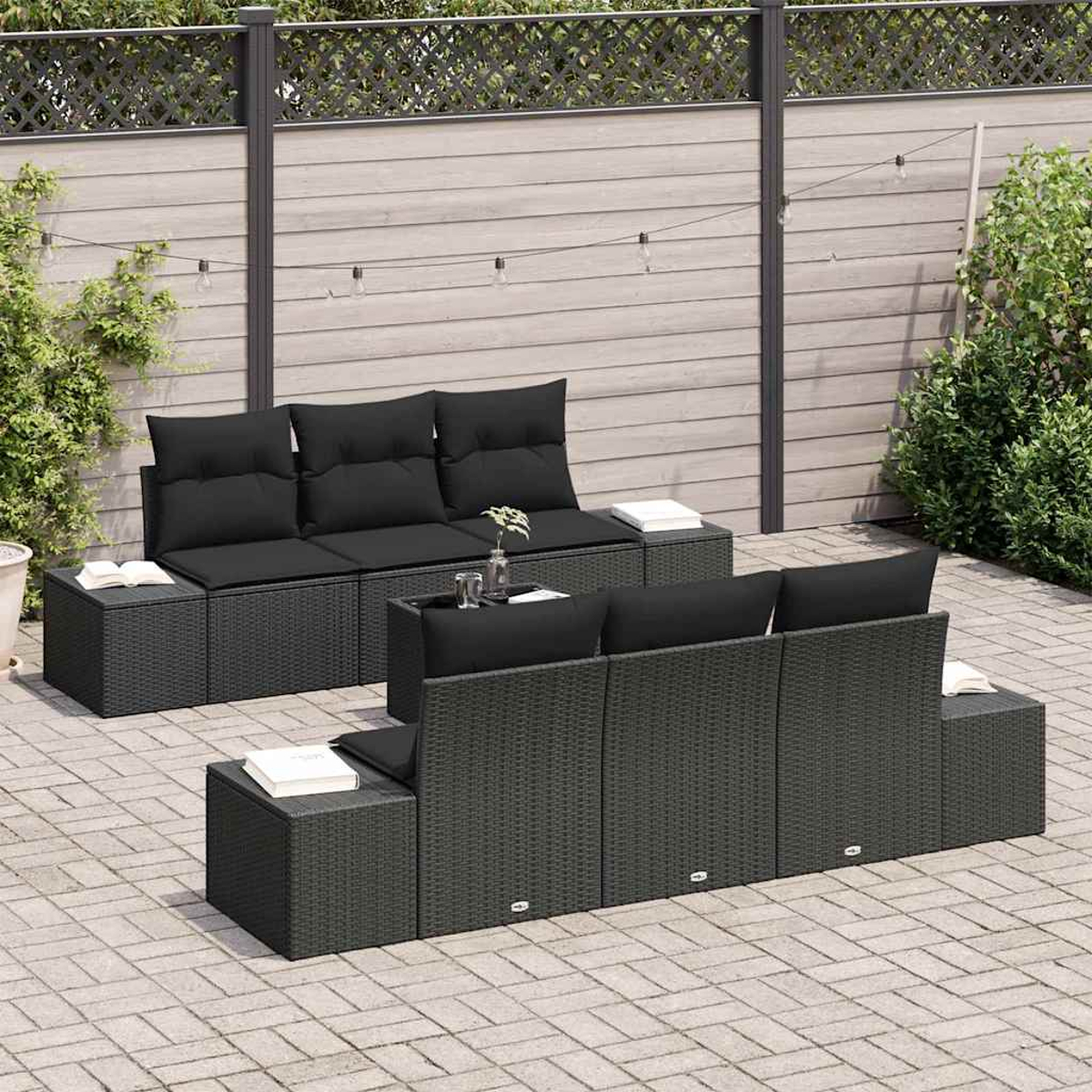 Gartenmöbel-Set mit schwarzen Kissen auf grauem Korbgeflecht. Enthält zwei Sofas, einen Tisch und eine graue Ziegelterrasse.