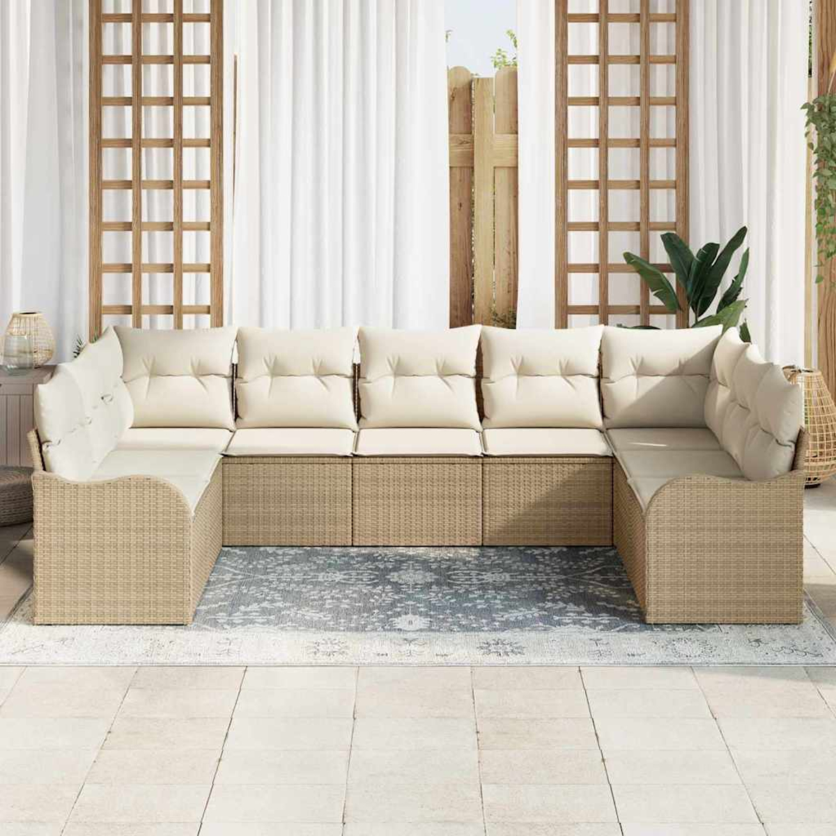 Ein Ecksofa aus Korbgeflecht mit cremefarbenen Kissen steht auf einem Teppich in einer Terrasse. Weiße Vorhänge und hölzerne Gitter im Hintergrund.