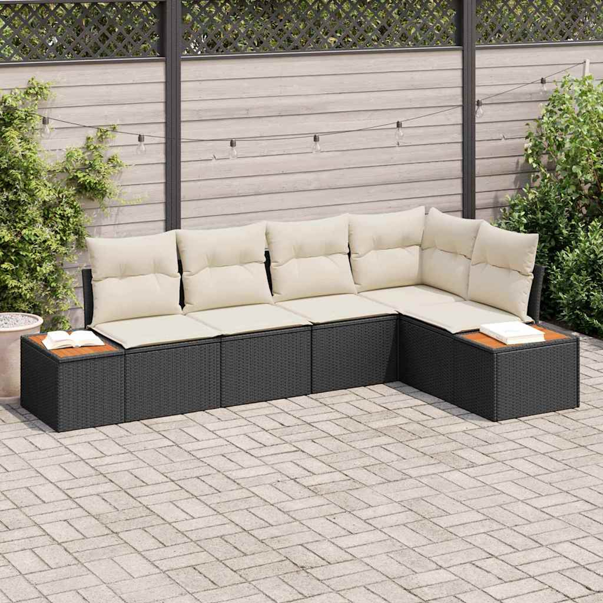 Ein Ecksofa mit cremefarbenen Kissen steht auf einer Terrasse. Im Hintergrund befinden sich ein Zaun und Grün.