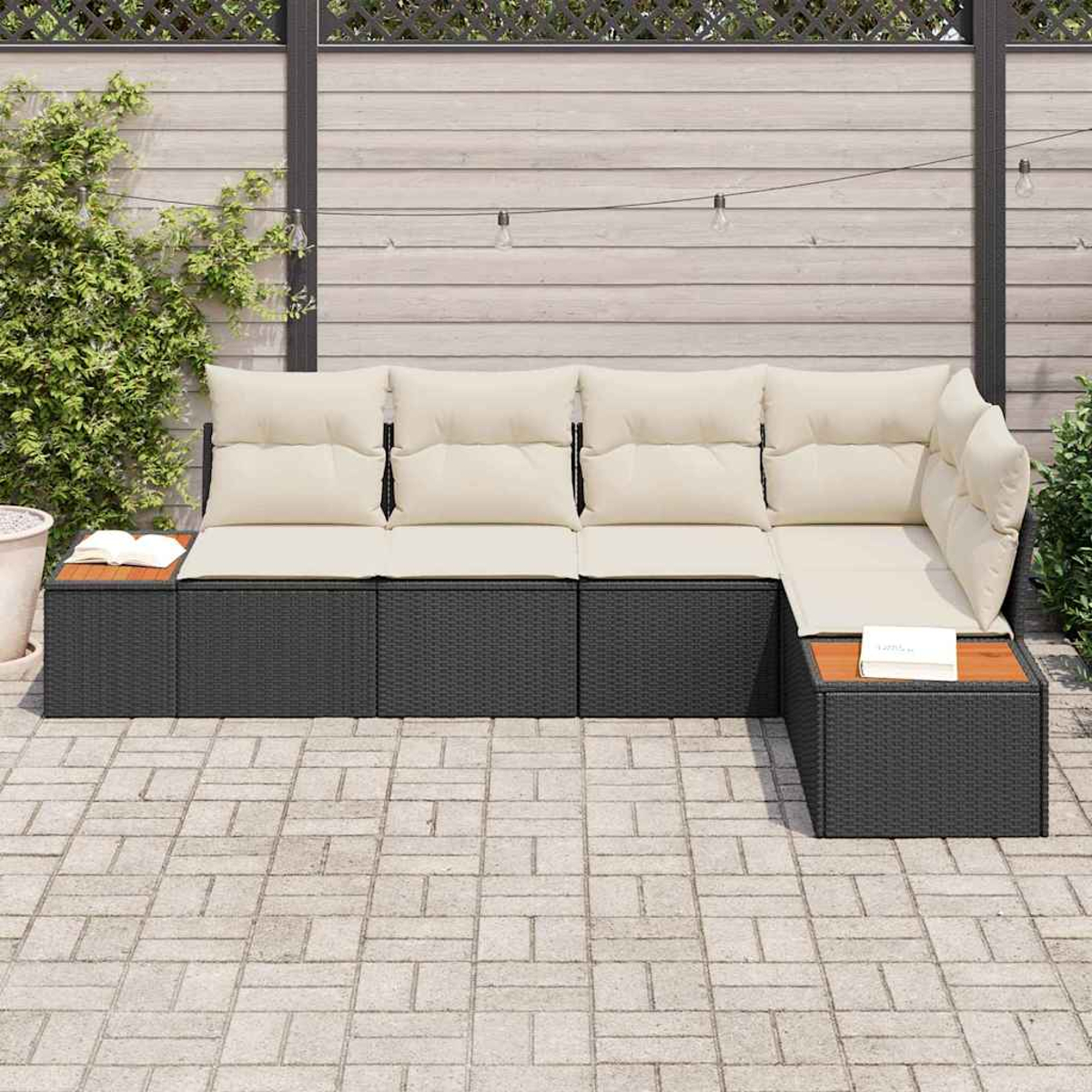 Ein Ecksofa im Freien mit cremefarbenen Kissen und dunklem Korbgeweberahmen. Es steht auf einer Ziegelterrasse mit einem Beistelltisch aus Holz.
