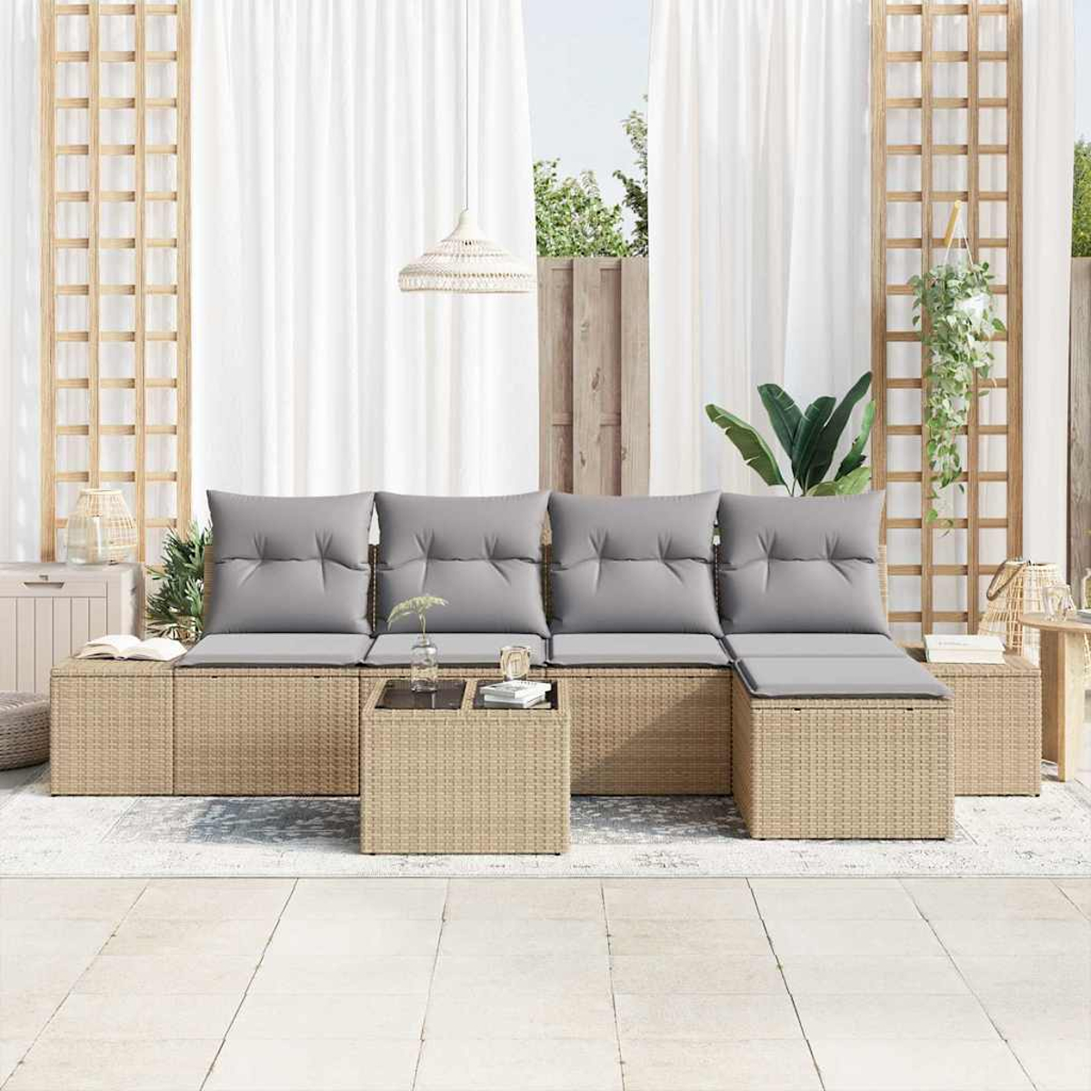 Outdoor-Rattan-Sofa mit grauen Kissen. Ein kleiner Tisch und eine Hängepflanze sind zu sehen. Weiße Vorhänge und ein Holzgitter dahinter.