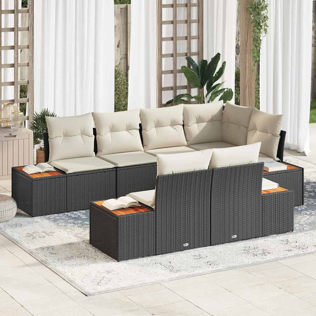 Outdoor-Ecksofa mit beigen Kissen auf einem gemusterten Teppich. Holztische, weiße Vorhänge und Pflanzen im Hintergrund.