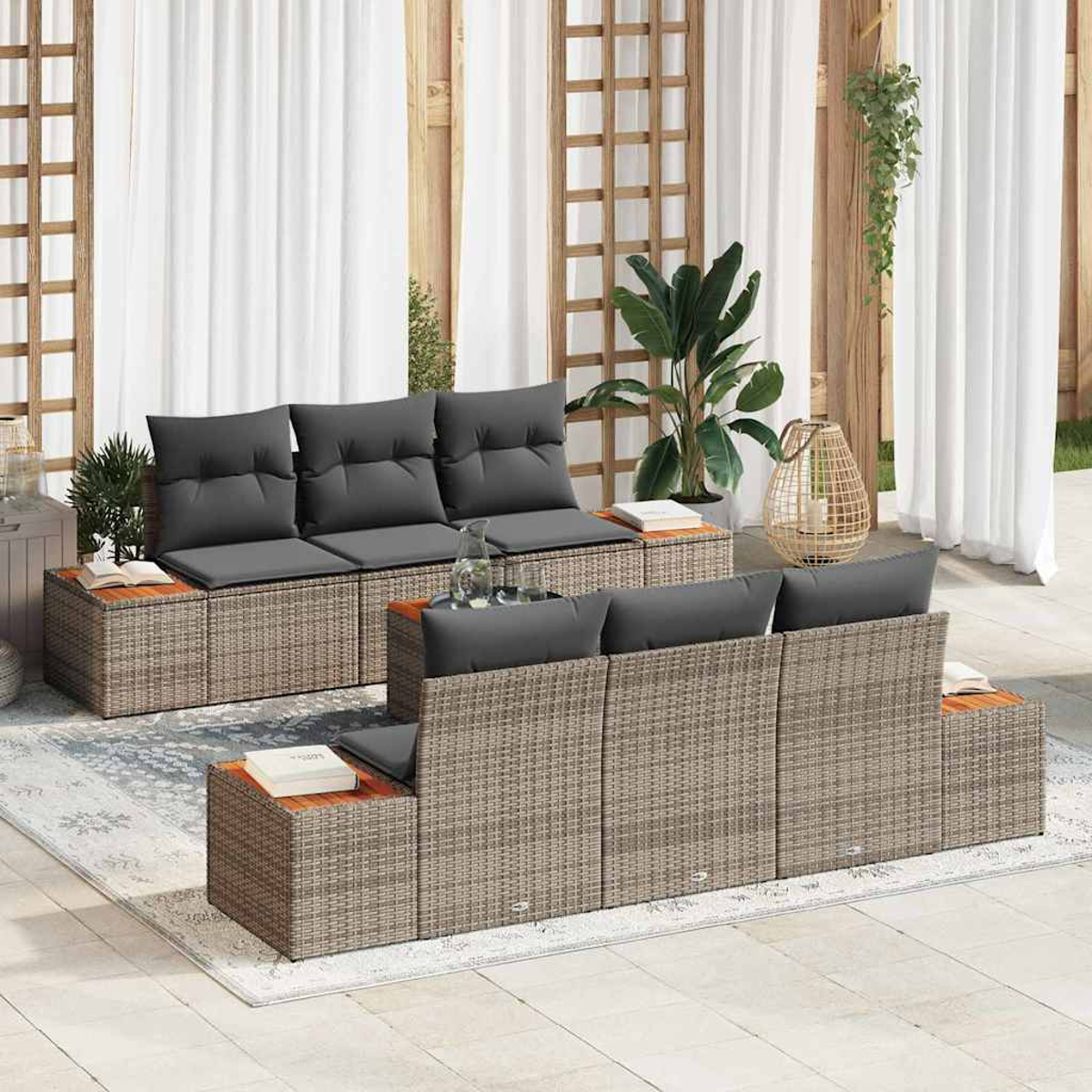 Gartenmöbel-Set aus Korbgeflecht mit grauen Kissen. Enthält zwei Sofas, Beistelltische und weiße Vorhänge im Hintergrund.