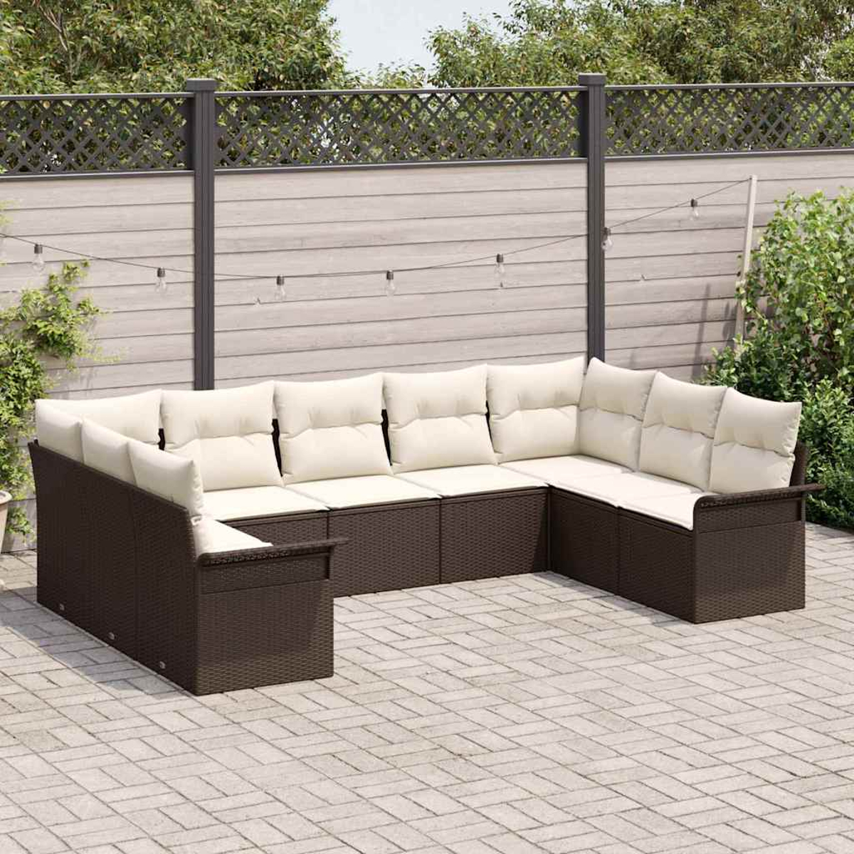 Ein braunes Rattan-Ecksofa mit cremefarbenen Kissen auf einer gepflasterten Terrasse, vor einem Holzzaun und Grün.
