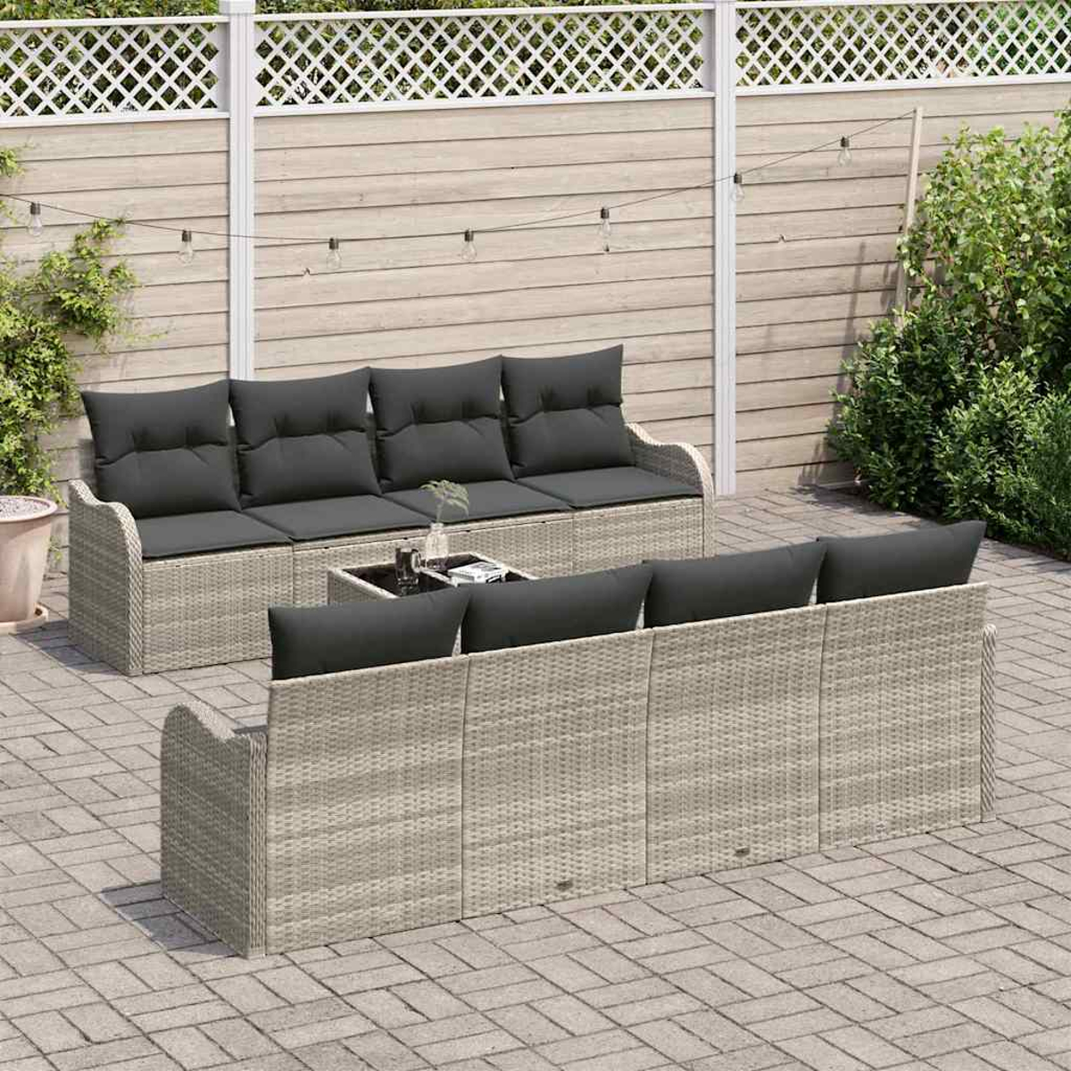 Garten-Terrassenset mit zwei grauen Korbsitzgruppen, schwarzen Kissen und einem kleinen Tisch. Auf einer Backsteinterrasse mit Zaunhintergrund.