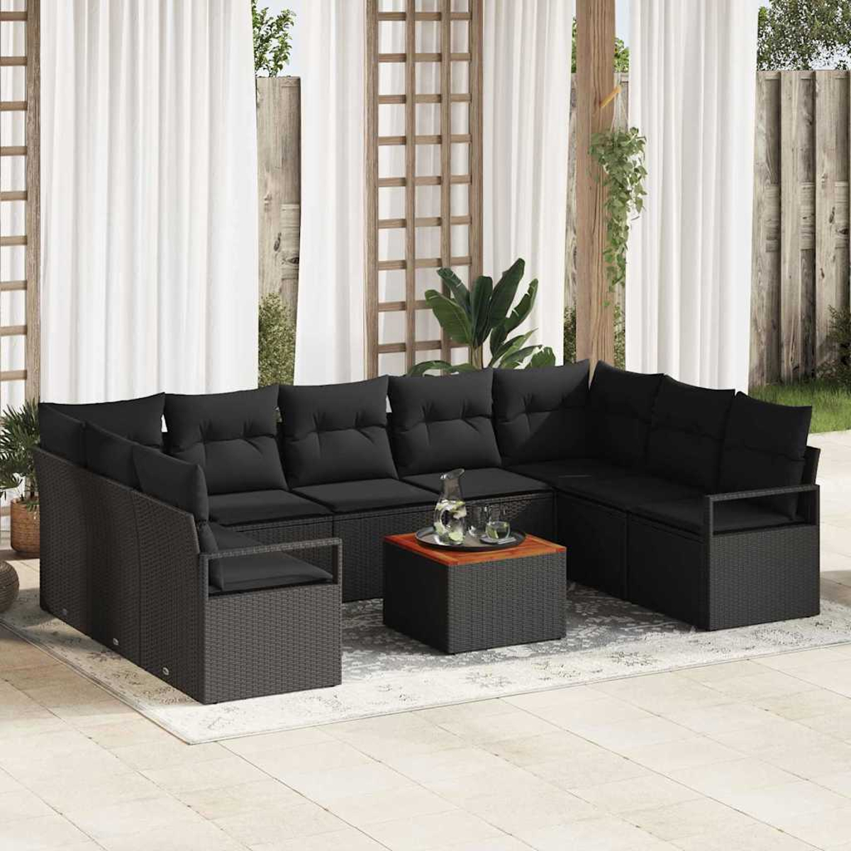 Outdoor-Terrassenset. Schwarzes Korbsessel-Sofa mit schwarzen Kissen. Ein kleiner Tisch und weiße Vorhänge im Hintergrund.