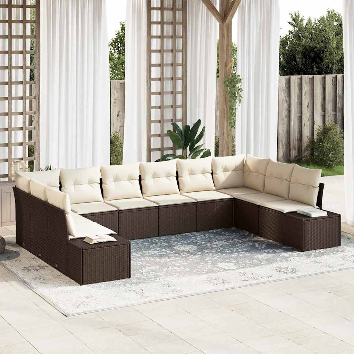 Ein Ecksofa im Freien mit beigen Kissen steht auf einem Teppich. Dahinter befinden sich weiße Vorhänge, Holzgitter und ein Holzzaun.