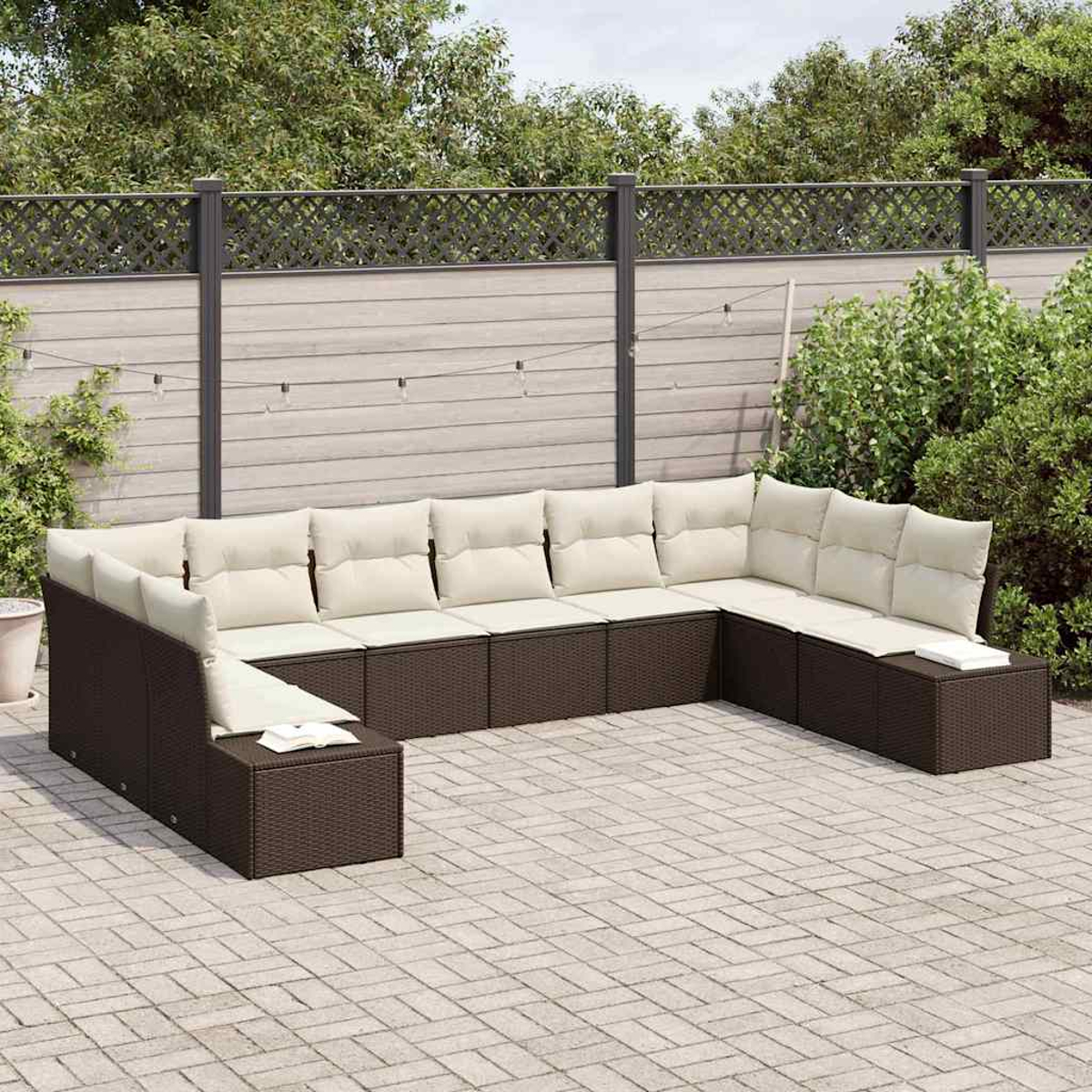 Ein großes, braunes Outdoor-Ecksofa aus Korbgeflecht mit cremefarbenen Kissen auf einer Terrasse, mit Zaun und Grün im Hintergrund.