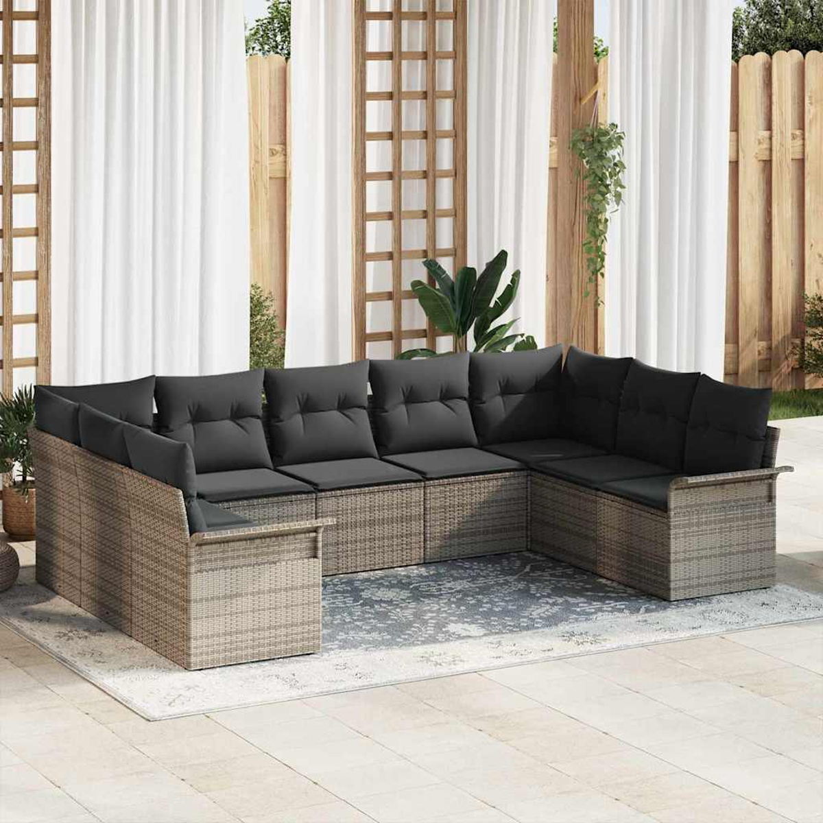 Ein U-förmiges Outdoor-Sofa mit grauen Kissen steht auf einem Teppich. Weiße Vorhänge und hölzerne Gitter und Zäune befinden sich im Hintergrund.