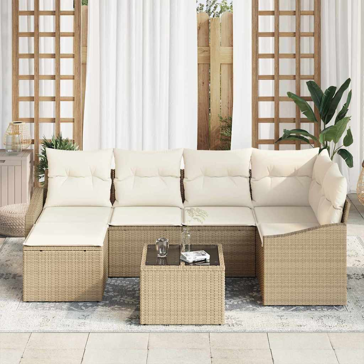 Ein Ecksofa mit cremefarbenen Kissen und einem passenden Couchtisch stehen auf einer Terrasse mit einem Teppich. Dahinter ein Fenster mit weißen Vorhängen.