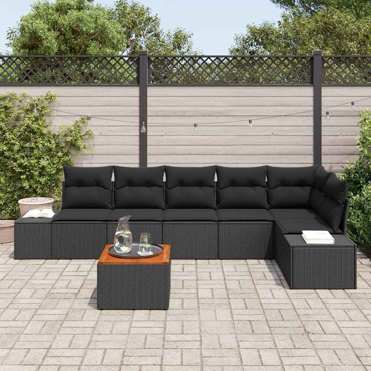Gartensektionssofa mit schwarzen Kissen, einem Couchtisch mit Tablett und einem Hinterhof mit Zaun.