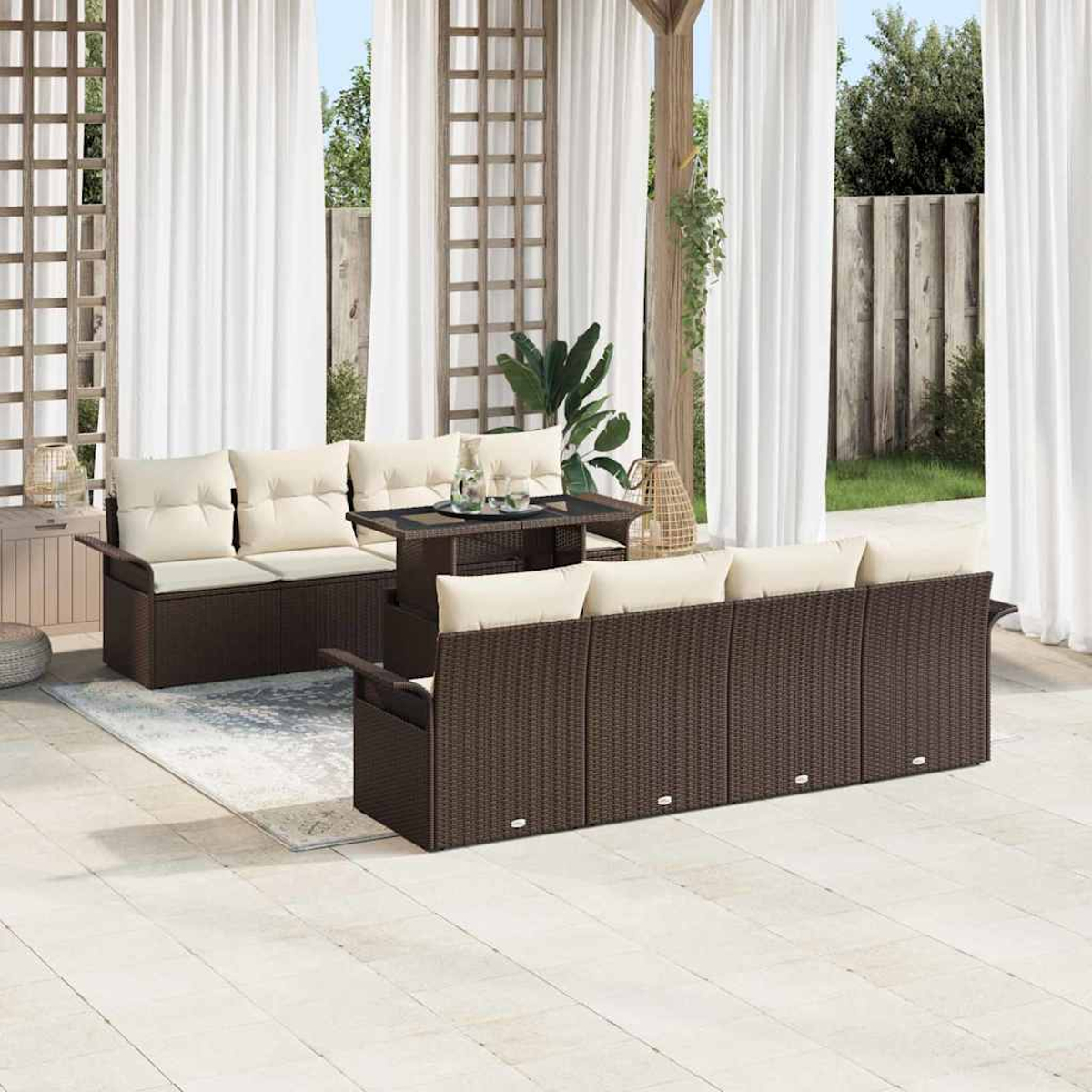 Juego de patio al aire libre con muebles de mimbre marrón y cojines crema. Incluye sofá, sofá de dos plazas y una mesa. Cortinas blancas al fondo.