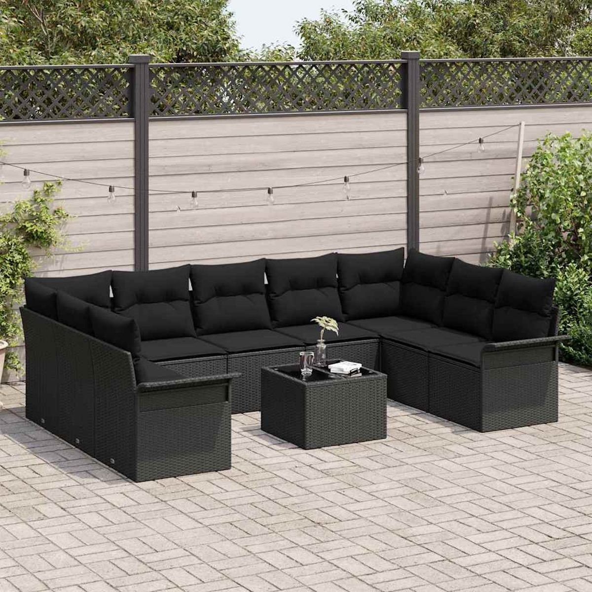 Garten-Sitzgruppe. Schwarzes Rattan-Ecksofa mit schwarzen Kissen, kleiner Tisch mit Getränken auf einer Terrasse. Holzzaun im Hintergrund.