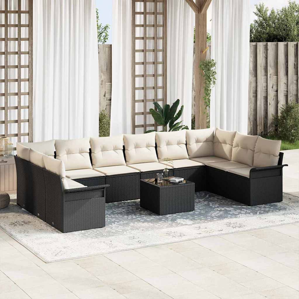 Outdoor-Ecksofa mit beigen Kissen und schwarzem Korbgewebe. Davor ein kleiner Tisch. Weiße Vorhänge im Hintergrund.
