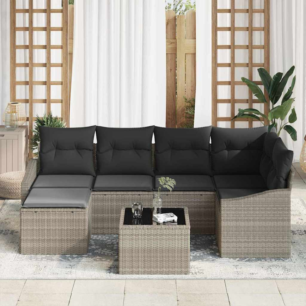 Outdoor-Ecksofa mit schwarzen Kissen. Ein kleiner Tisch mit Glasplatte und zwei Gläsern. Vorhänge und eine Pflanze im Hintergrund.