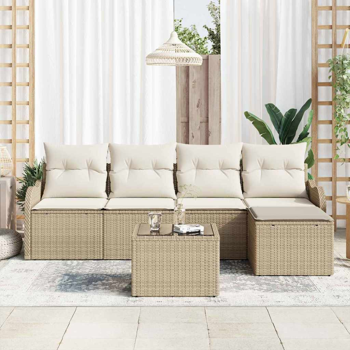 Garten-Sitzgruppe mit beigefarbenen Kissen. Besteht aus Sofa, Couchtisch und Beistelltisch. Im Hintergrund weiße Vorhänge und Pflanzen.