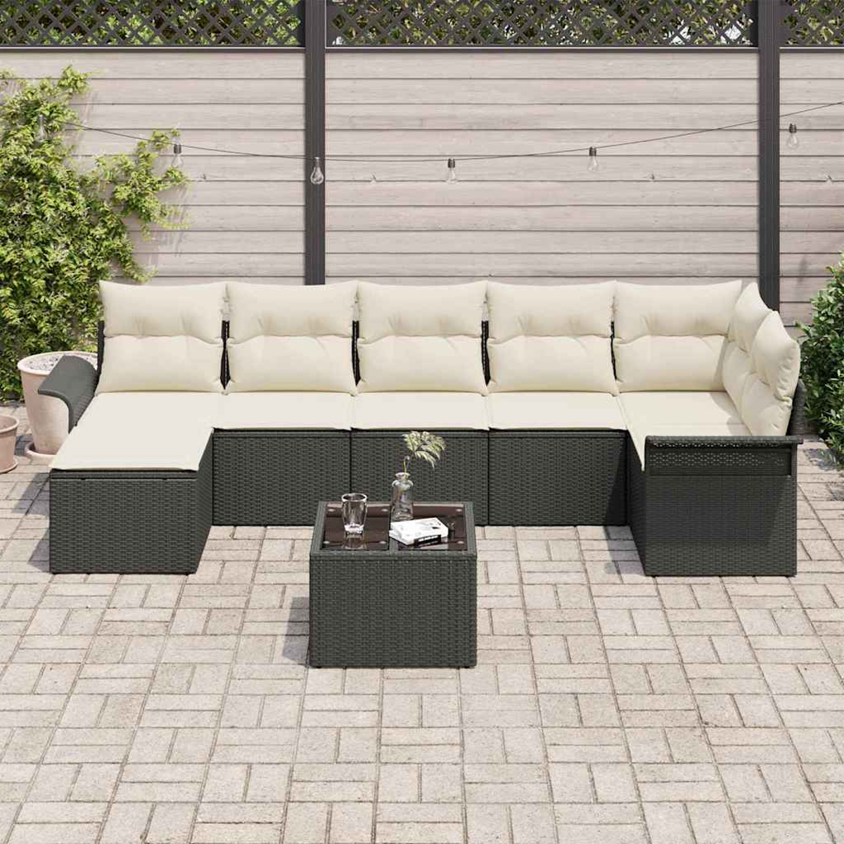 Juego de muebles de patio con un sofá seccional y una mesa pequeña. El sofá tiene cojines crema y estructura gris oscura.