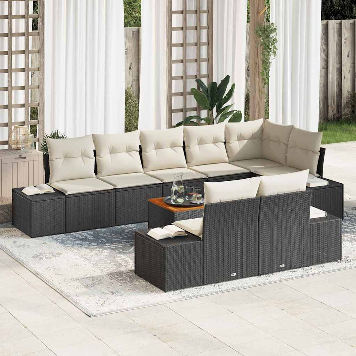 Outdoor-Ecksofa mit cremefarbenen Kissen. Ein kleiner Holztisch hält Getränke bereit. Weiße Vorhänge und Grünzeug sind im Hintergrund.