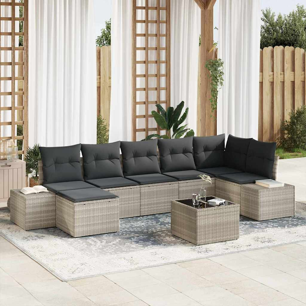 Outdoor-Sitzbereich mit grauem Ecksofa, Kissen und Couchtisch. Weiße Vorhänge und eine Holzpergola befinden sich im Hintergrund.