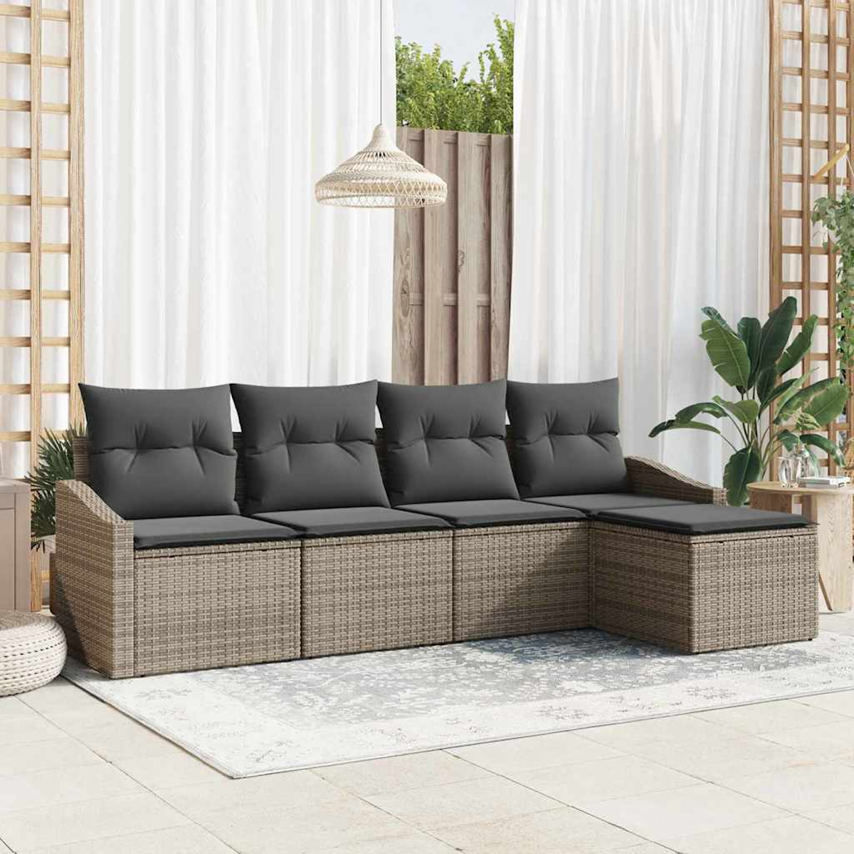 Rattan-Sofa für draußen mit grauen Kissen. Weiße Vorhänge im Hintergrund, mit Hängelampe und Pflanzen.