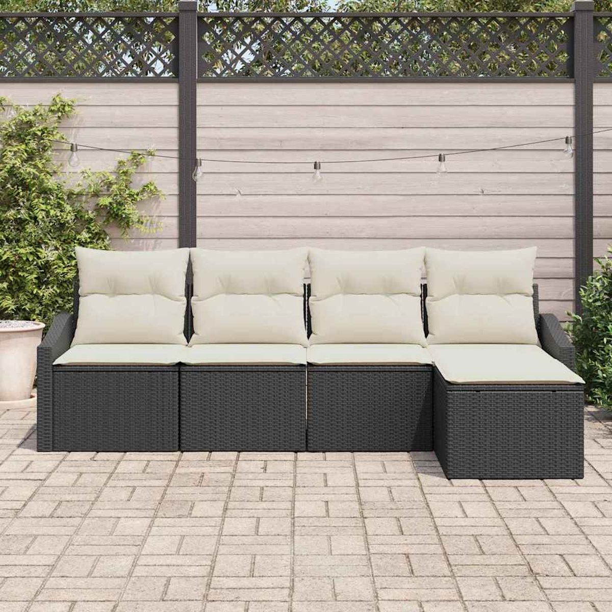 Outdoor-Ecksofa mit cremefarbenen Kissen. Schwarze Korbmöbel stehen auf einer Ziegelterrasse. Im Hintergrund ist ein Holzzaun.