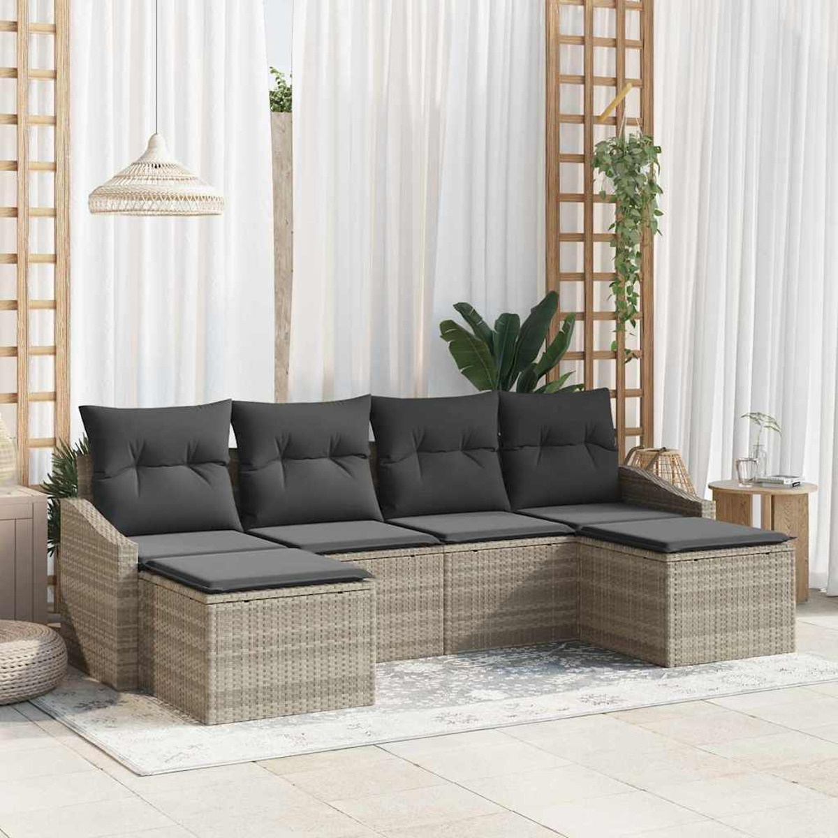 Outdoor-Sitzgruppe mit grauen Kissen. Beiges Rattan-Sofa mit Kissen auf einem Teppich. Weiße Vorhänge und Holzgitter im Hintergrund.