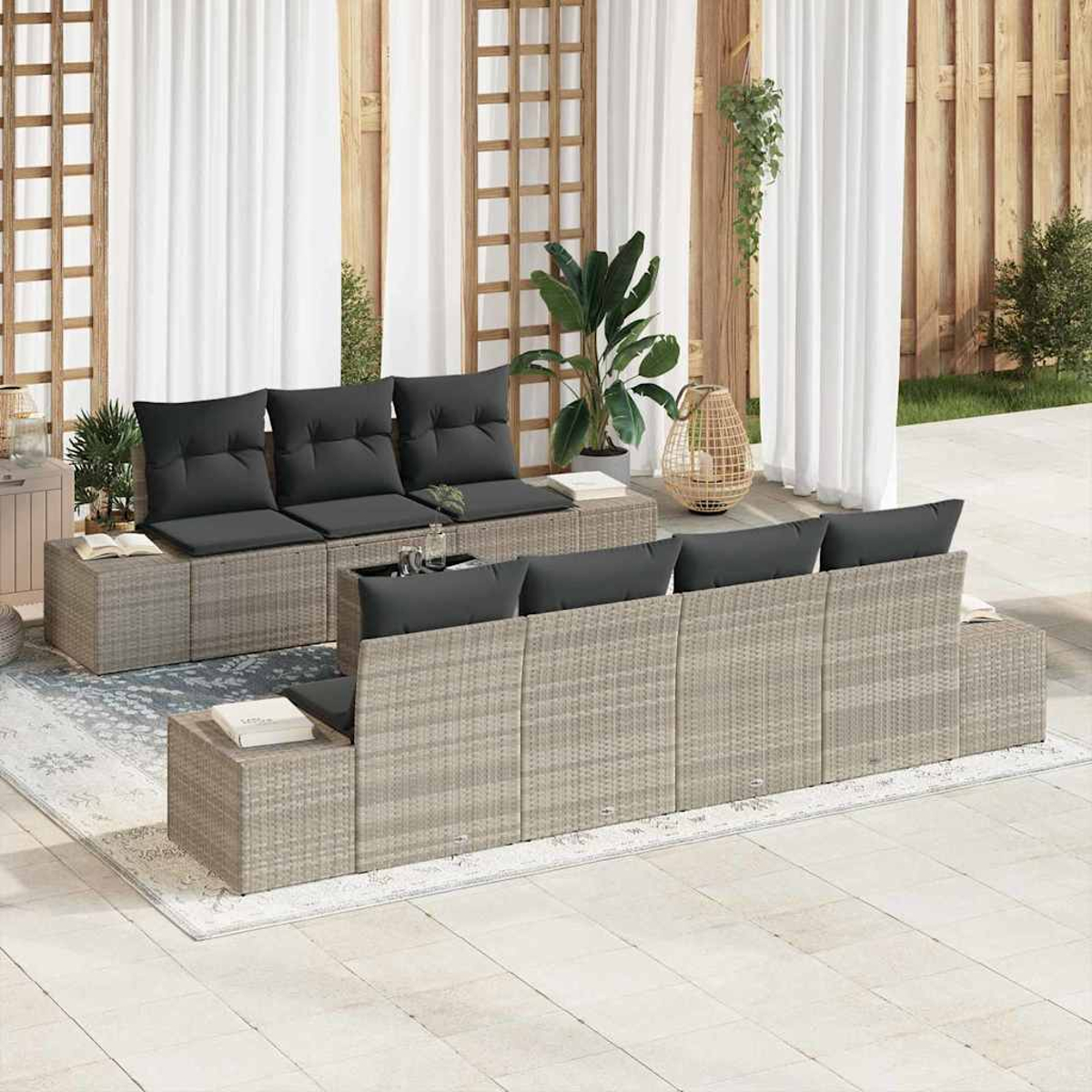 Garten-Terrassenset mit grauen Korbmöbeln, schwarzen Kissen und Pflanzen. Weiße Vorhänge und Holzgitter im Hintergrund.