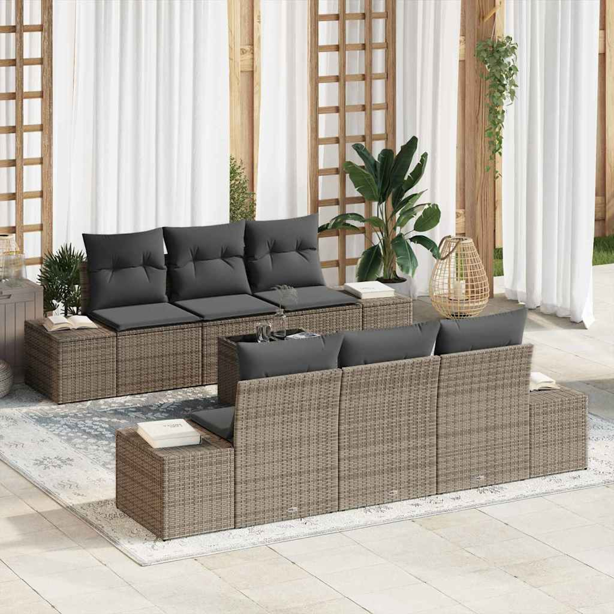 Outdoor-Sitzgruppe. Korbsessel mit grauen Kissen stehen auf einer Terrasse. Weiße Vorhänge und Pflanzen im Hintergrund.