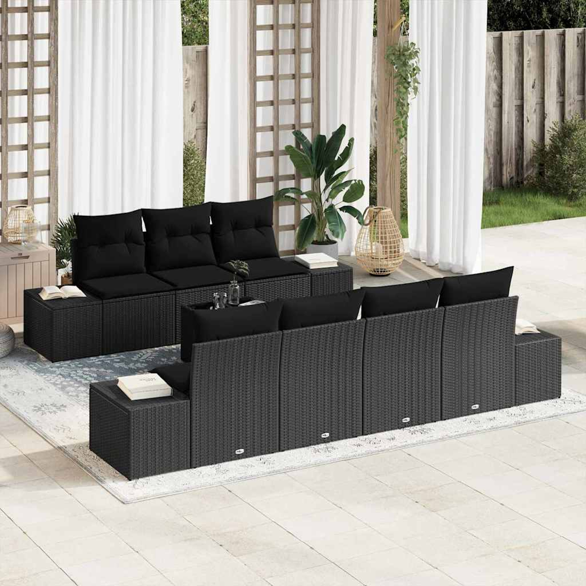 Garten-Sitzgruppe mit schwarzen Kissen. Enthält Sofas, Ottomanen und einen Teppich. Im Hintergrund Vorhänge, Pflanzen und eine Gitterstruktur.